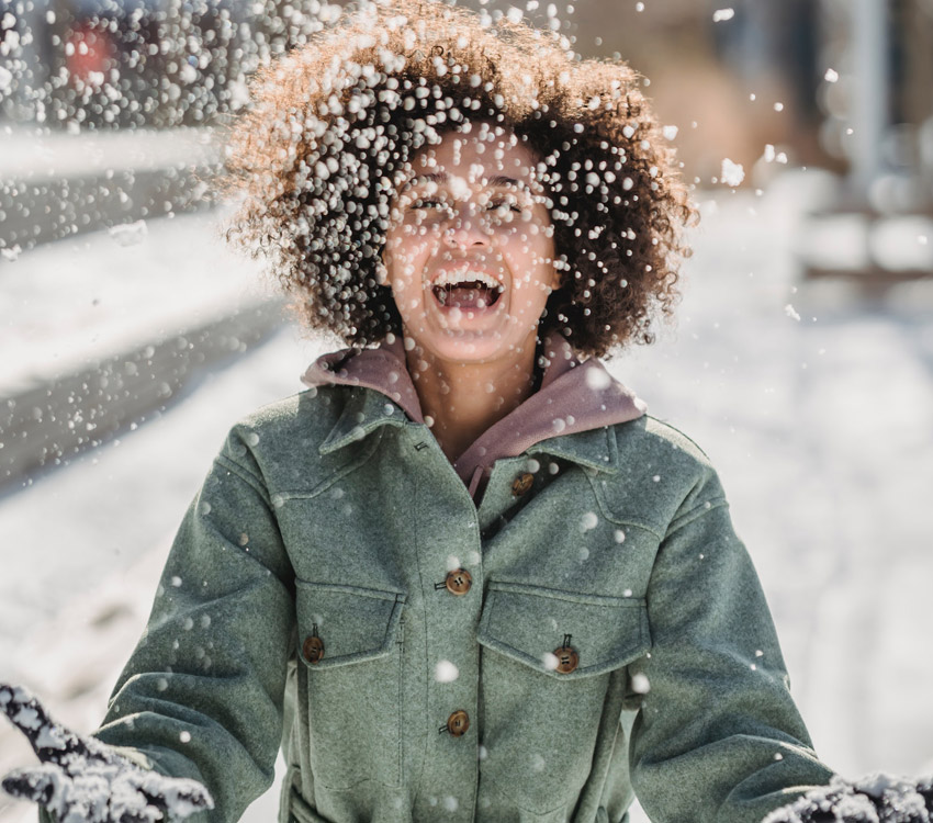 Young woman outside in winter playing with snow